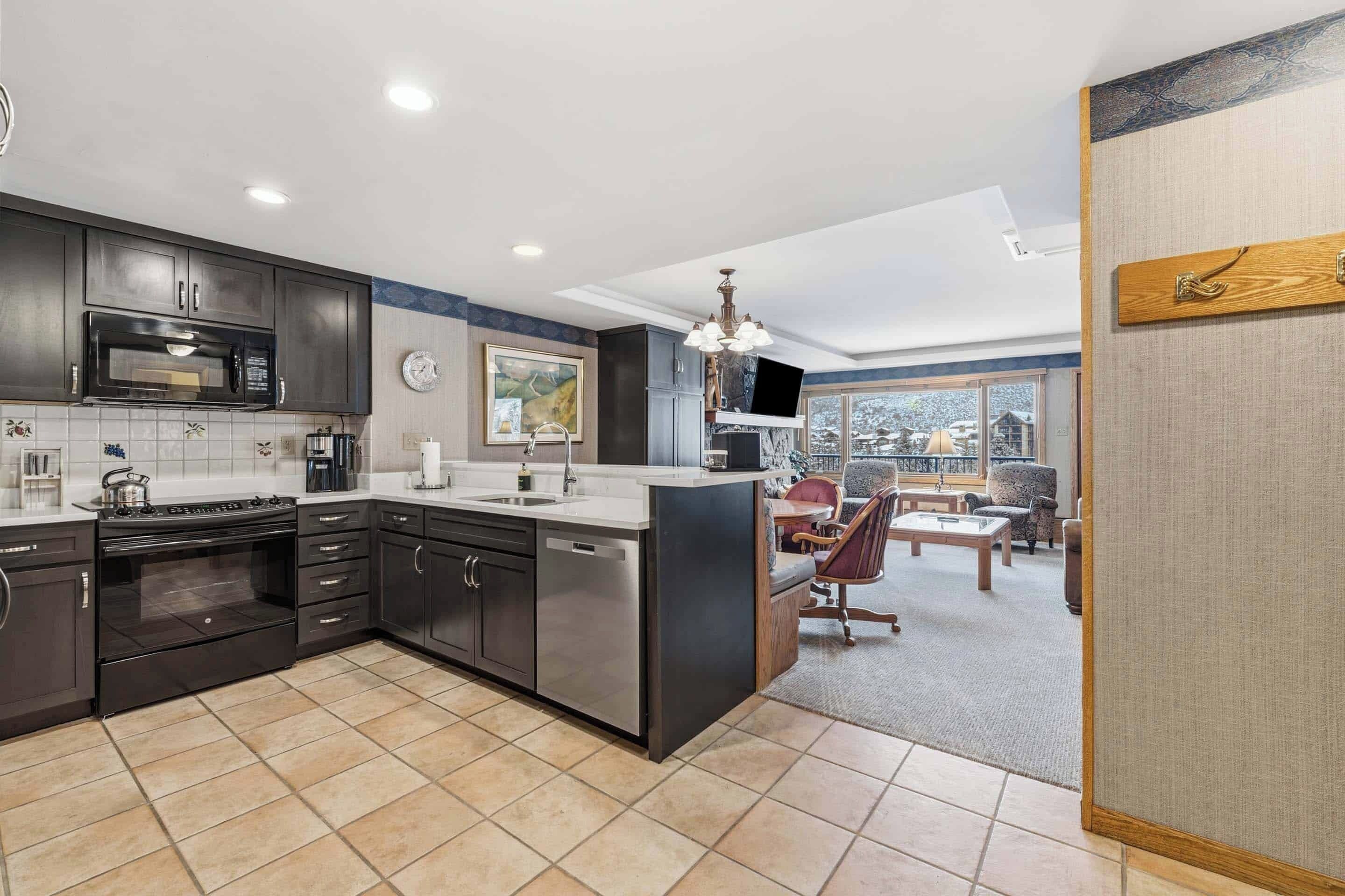A modern kitchen with dark cabinetry, a stainless steel stove, and a large island.