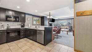 A modern kitchen with dark cabinetry, a stainless steel stove, and a large island.