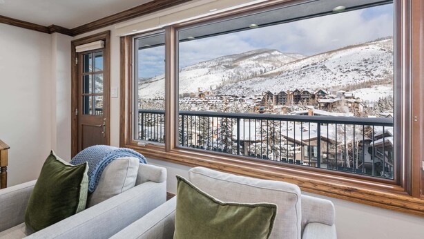 A cozy living room with a large window overlooking a snowy mountain town.