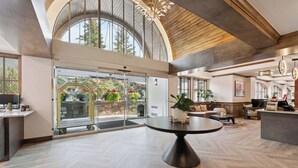 A spacious lobby with a large round table, a reception desk, and a view of the outdoors through a glass door. - Lodge Tower 687 3BR at the base of Vail Mountain (Vail)
