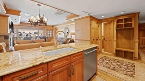 A spacious kitchen with granite countertops, wooden cabinets, and a built-in dishwasher.
