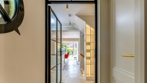 Un corridoio con una porta in vetro, una sedia rossa e un mobile contenitore.