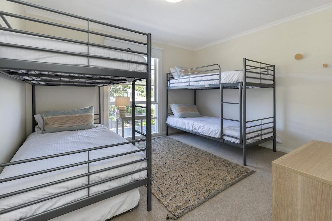 A room with two bunk beds, a small wooden cabinet, and a rug.