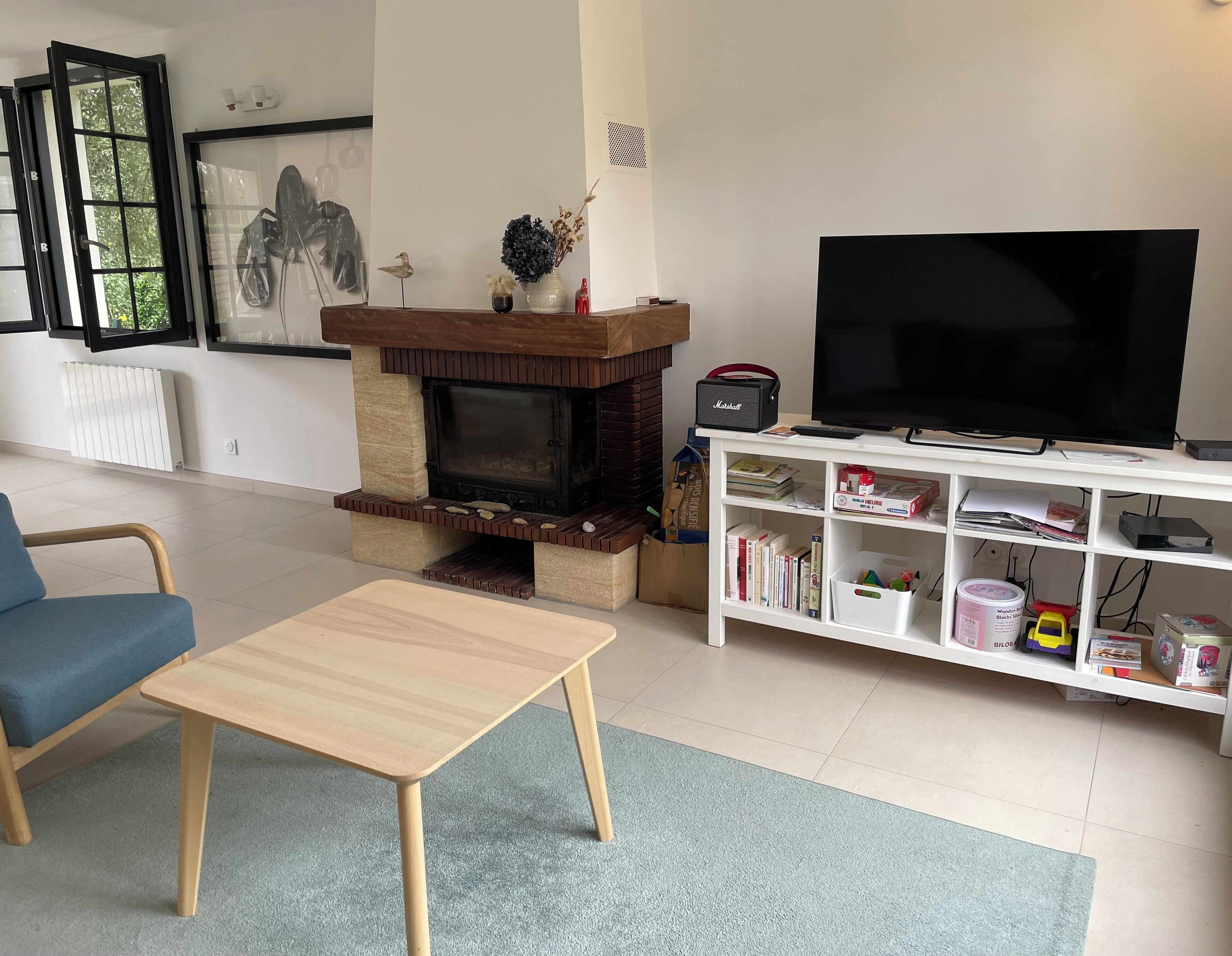 A living room with a fireplace, a television, a bookshelf, and a blue chair.