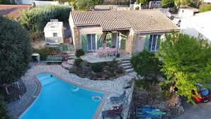 A swimming pool with lounge chairs, a covered patio, and a stone pathway. - Maison Individuelle de Caractère (Roquebrune-sur-Argens)