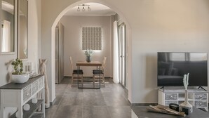 Een moderne woonkamer met een televisie, een eettafel met stoelen en een decoratieve vaas.