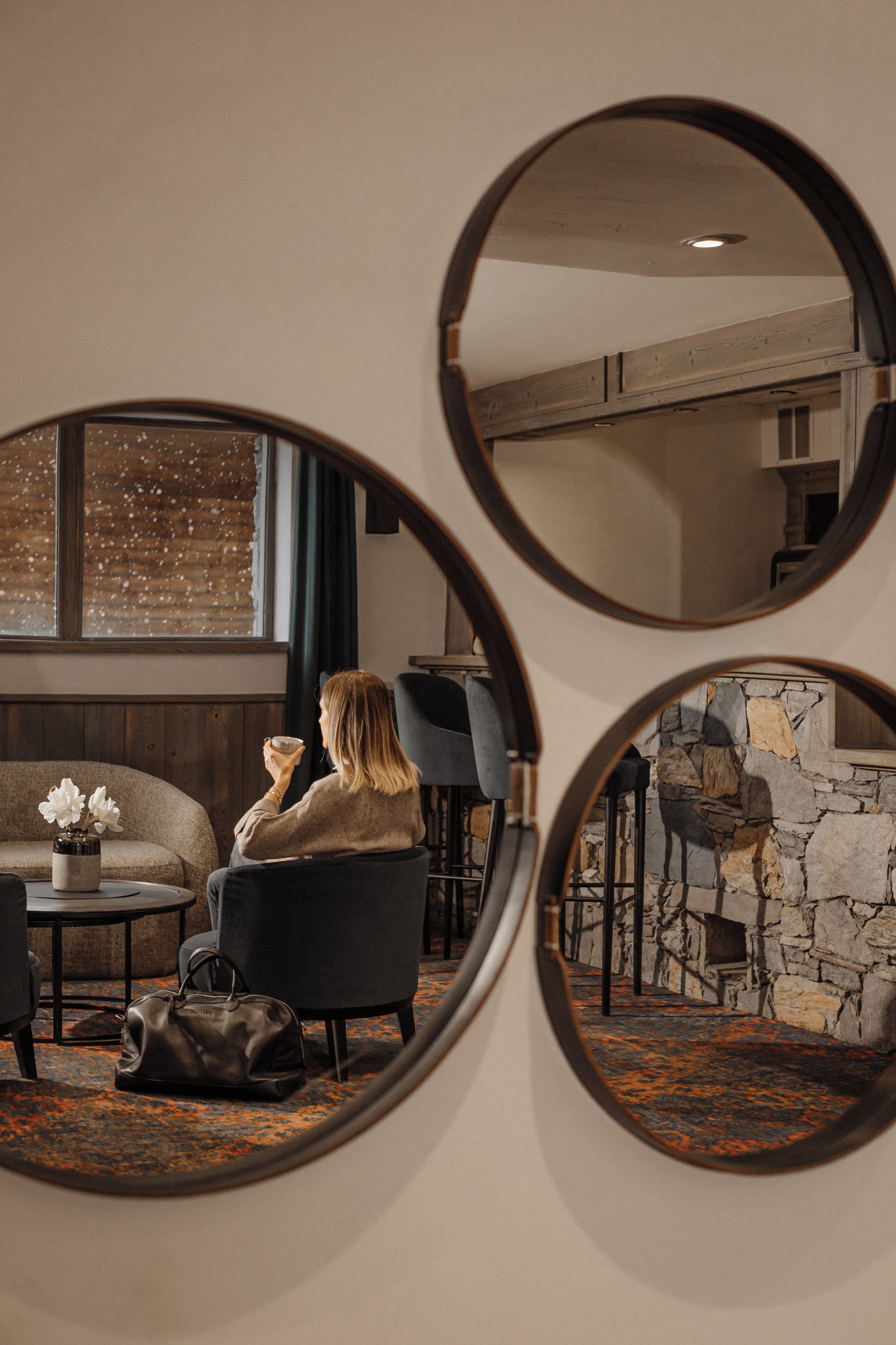 Une pièce comprenant un canapé, un fauteuil, une table et un miroir qui reflète l’intérieur.