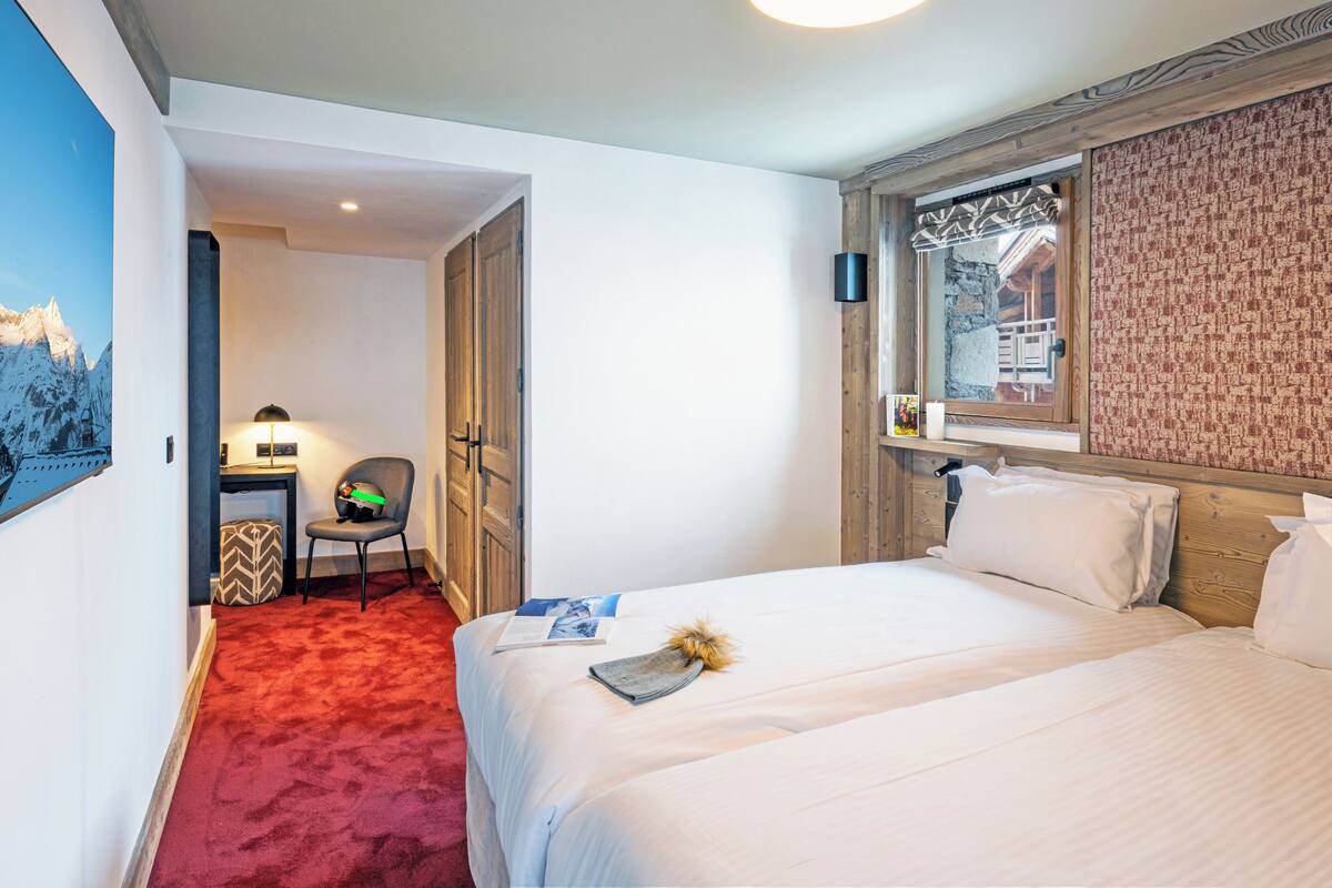 Una habitación de hotel con una cama, una silla, un escritorio y un televisor montado en la pared.