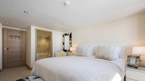 Une chambre à coucher avec un grand lit, des tables de chevet, un miroir et une armoire.