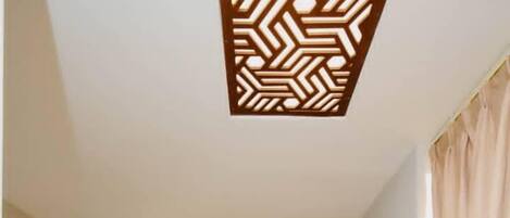 Un pasillo de hotel con una puerta roja, un escritorio de madera y una cortina color crema.
