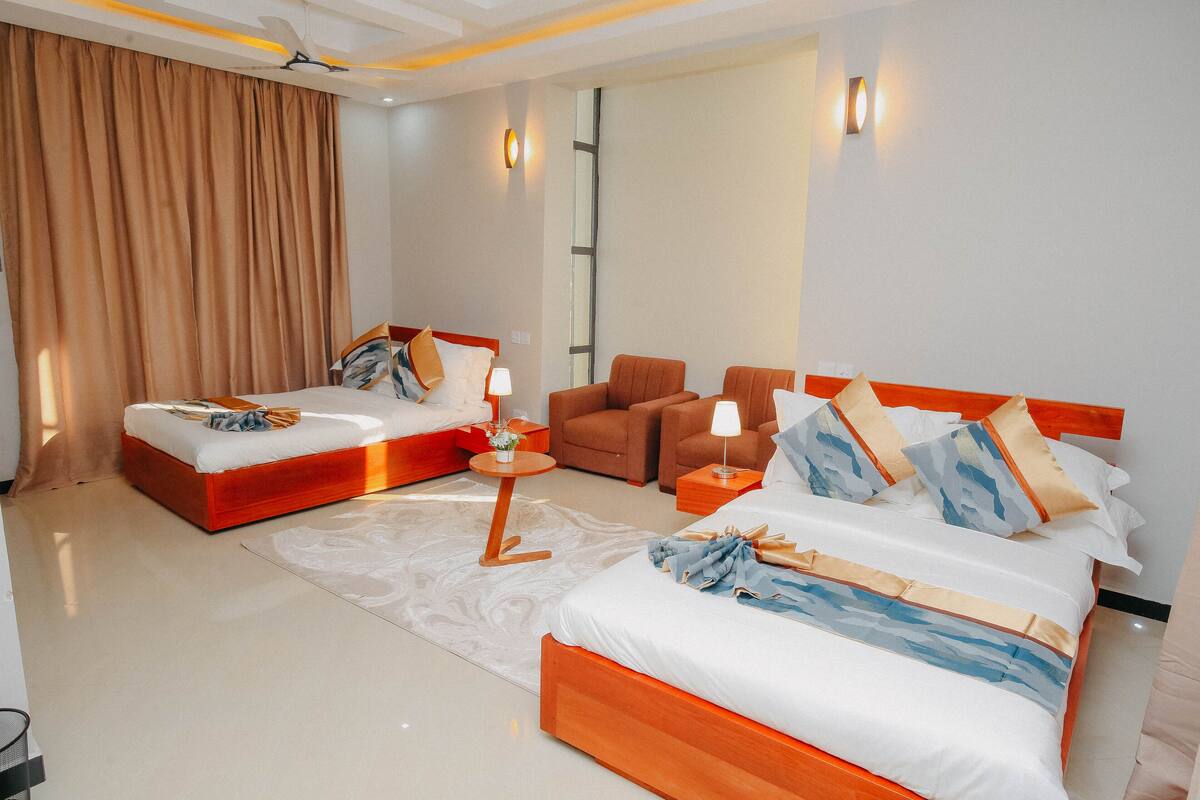 Une chambre d’hôtel avec deux lits, un canapé, une petite table et un miroir.