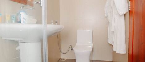 Un baño con lavamanos, inodoro y cabina de ducha de vidrio.