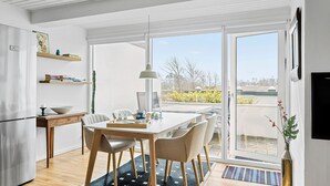 Een moderne keuken met een eethoek, grote ramen en uitzicht op de omgeving.