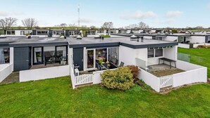 Een moderne, verplaatsbare woning met een plat dak, grote ramen en een klein terras.