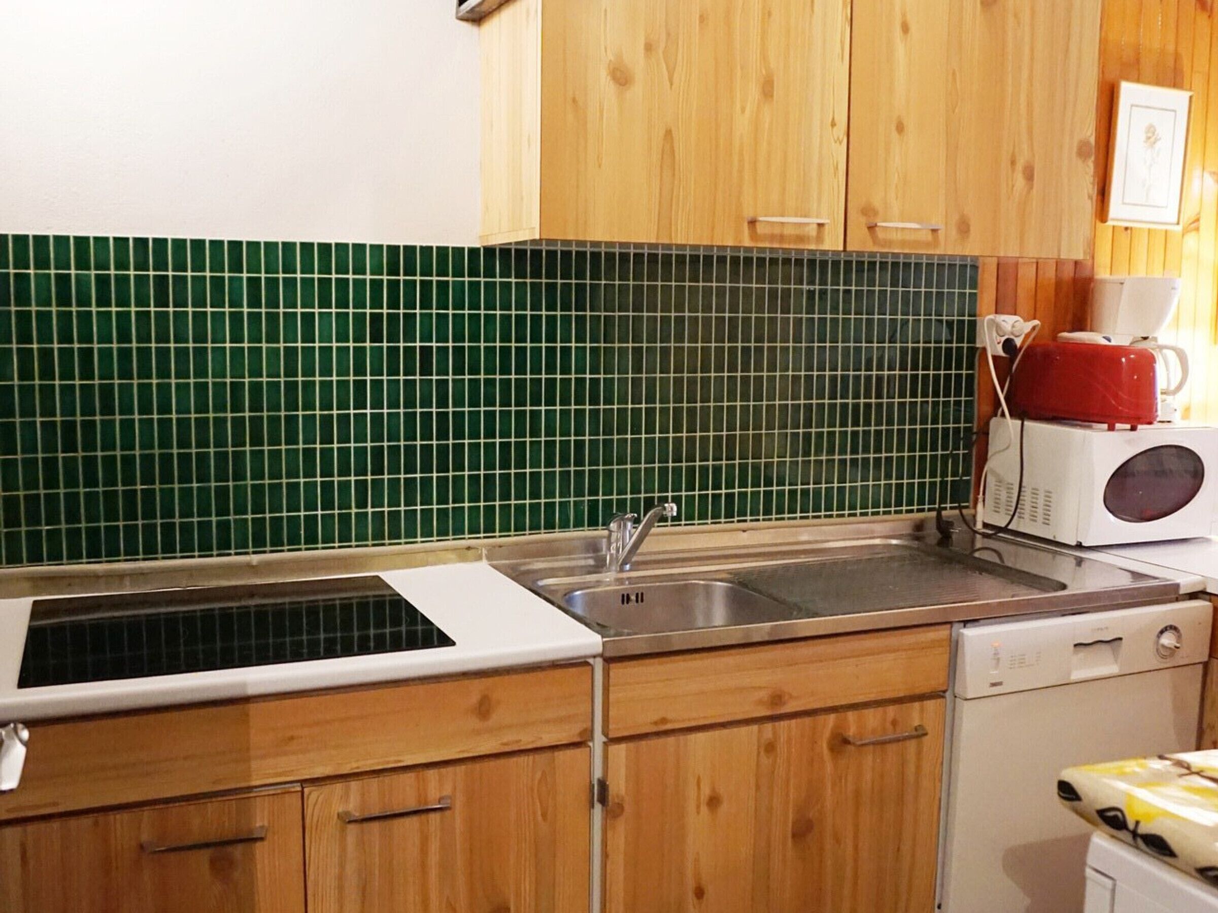 Una cocina con armarios de madera, un fregadero, un microondas y un salpicadero de azulejos.