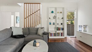 Una sala moderna con un sofá gris, una estantería blanca y una mesa de centro con objetos decorativos.