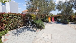 Un camino pavimentado con una bicicleta, una silla roja y un carrito.