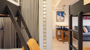 A modern room with a bunk bed, a small table with chairs, and a sofa.