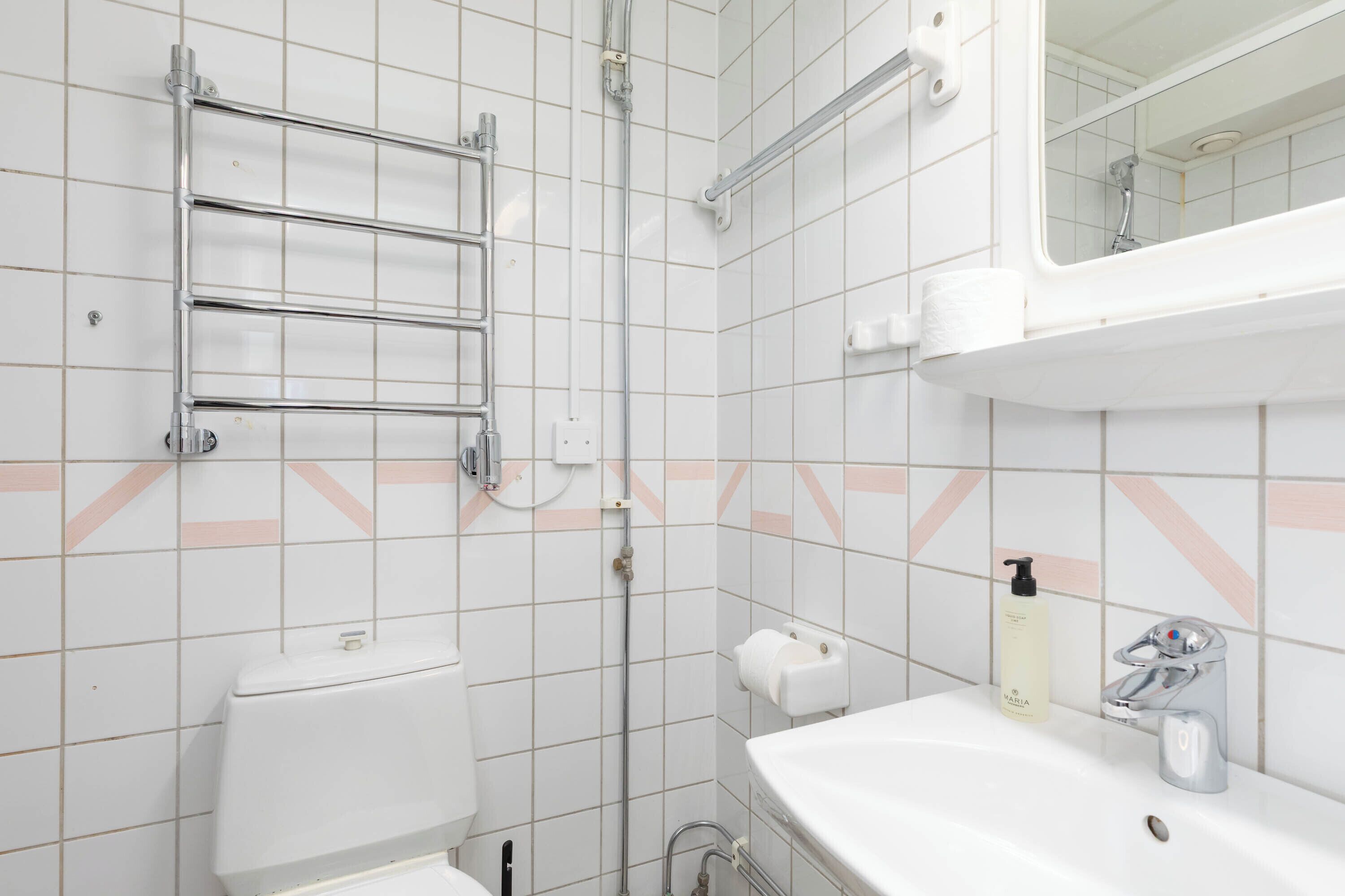 A bathroom with a toilet, a sink, a mirror, a towel rack, and a shower.