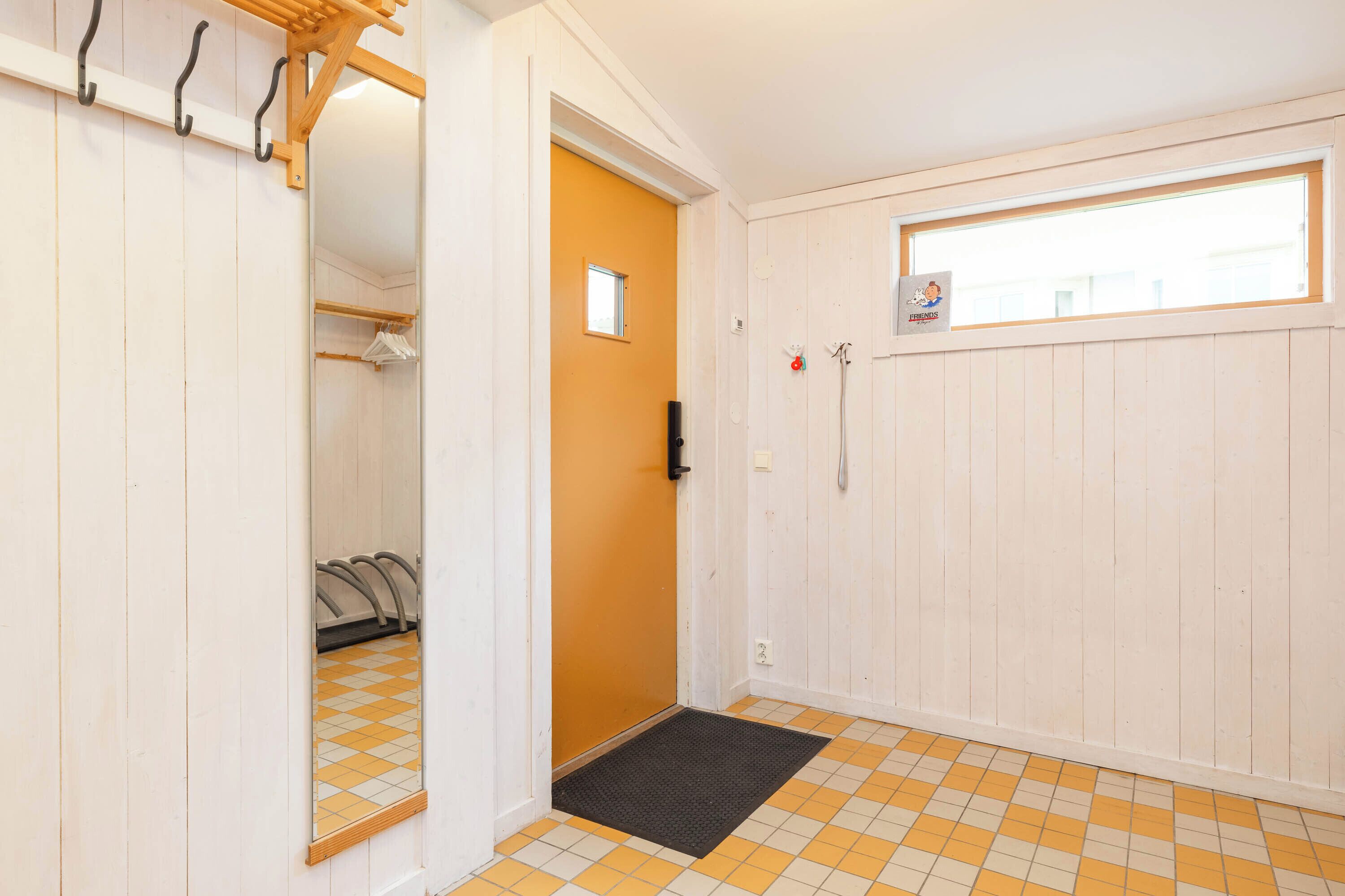 A hallway with a door leading to a room, a coat rack, and a window with a view.