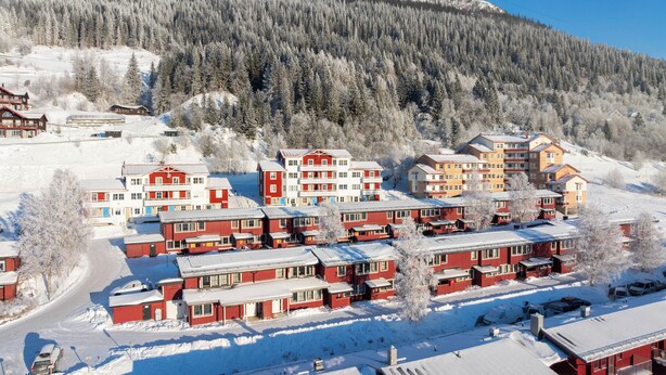 A snow-covered residential area with multiple red and white buildings, likely a ski resort or mountain village.