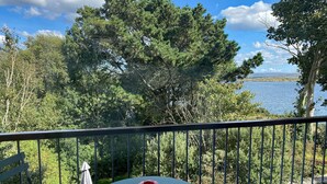 Een balkon met een tafel en stoel, met uitzicht op water en bomen.