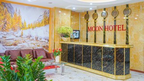 Un área de recepción de hotel con un mostrador de mármol, un mural grande de un paisaje invernal y un sofá.
