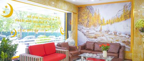 A lobby with a red sofa, a brown sofa, and a striped sofa. There is a vase with flowers on a table.