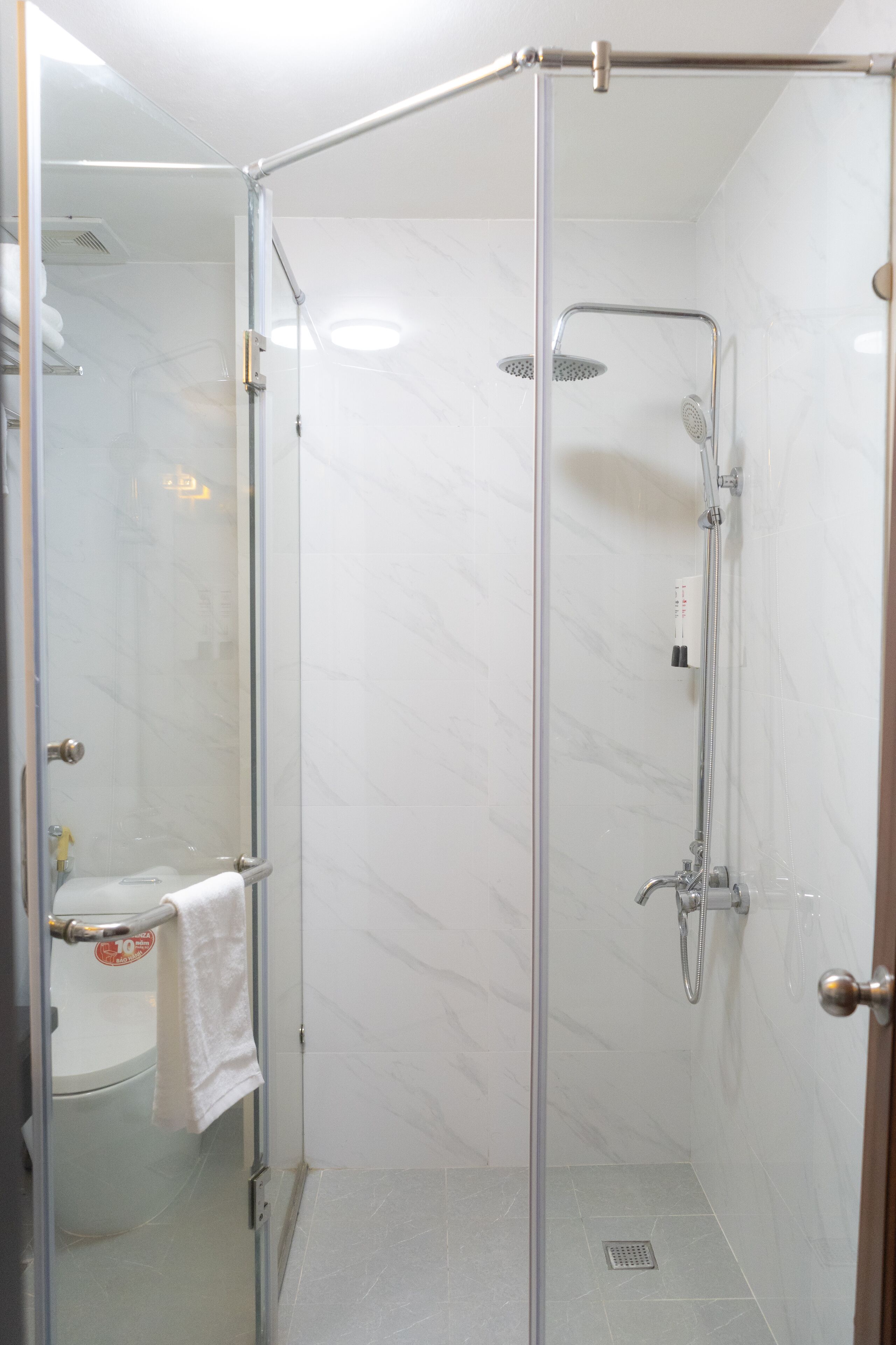 A glass-enclosed shower stall with a handheld showerhead and a wall-mounted faucet.