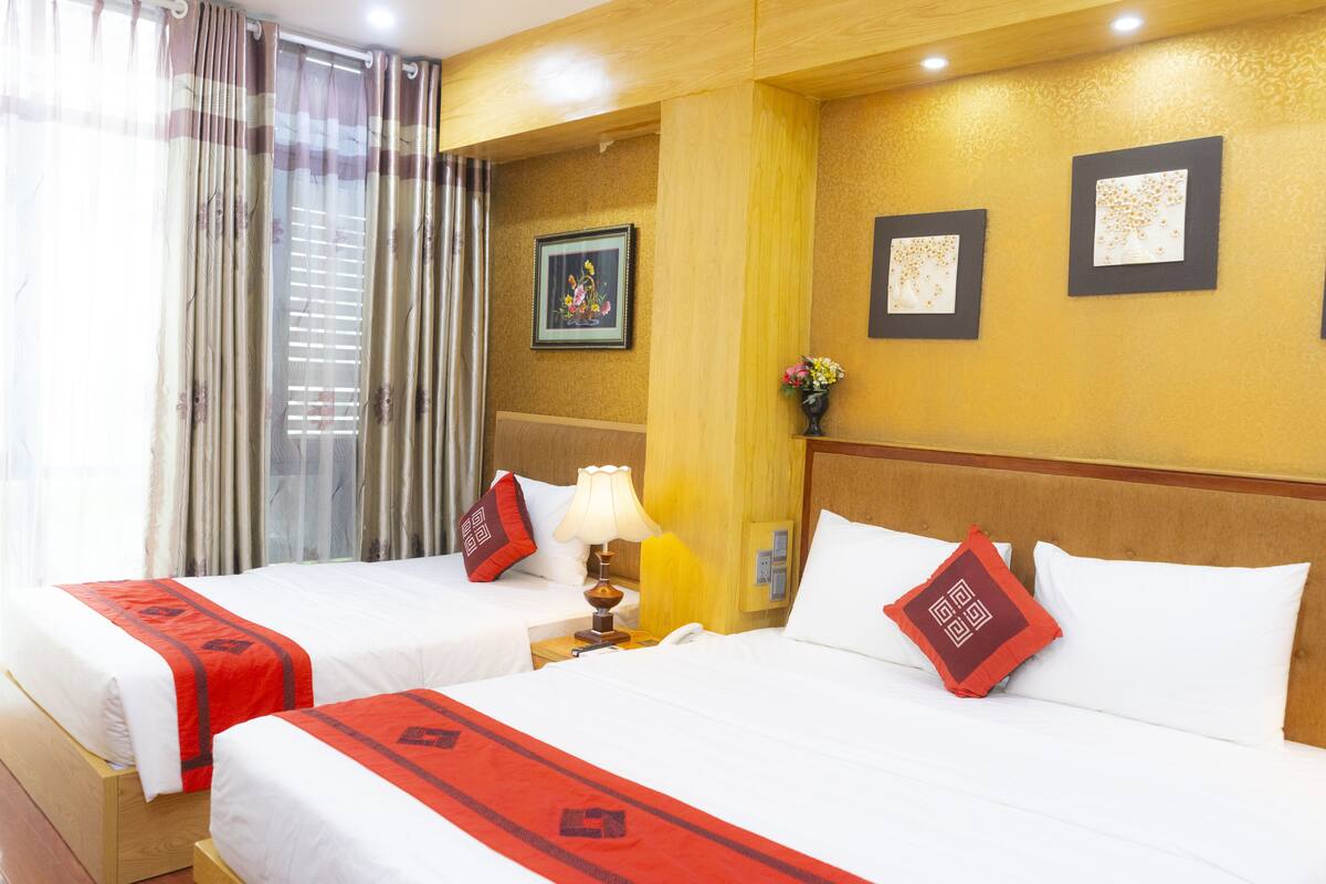 A hotel room with two beds, a nightstand with a lamp, and a wall with framed artwork.