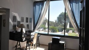 A room with a desk, chair, and a view of a swimming pool.