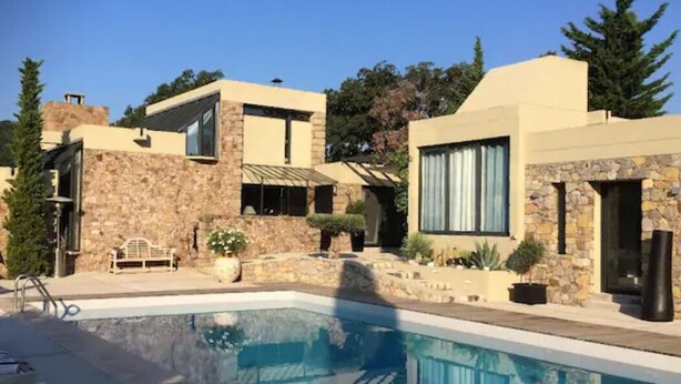 A modern house with a swimming pool, stone walls, and a patio area.