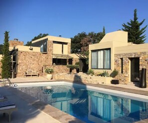 Uma casa moderna com piscina, paredes de pedra e área de pátio.