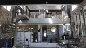 A spacious interior with a central staircase, a chandelier, and a dining area.