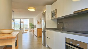 Une cuisine moderne avec des meubles blancs, des appareils en acier inoxydable et une table en bois.