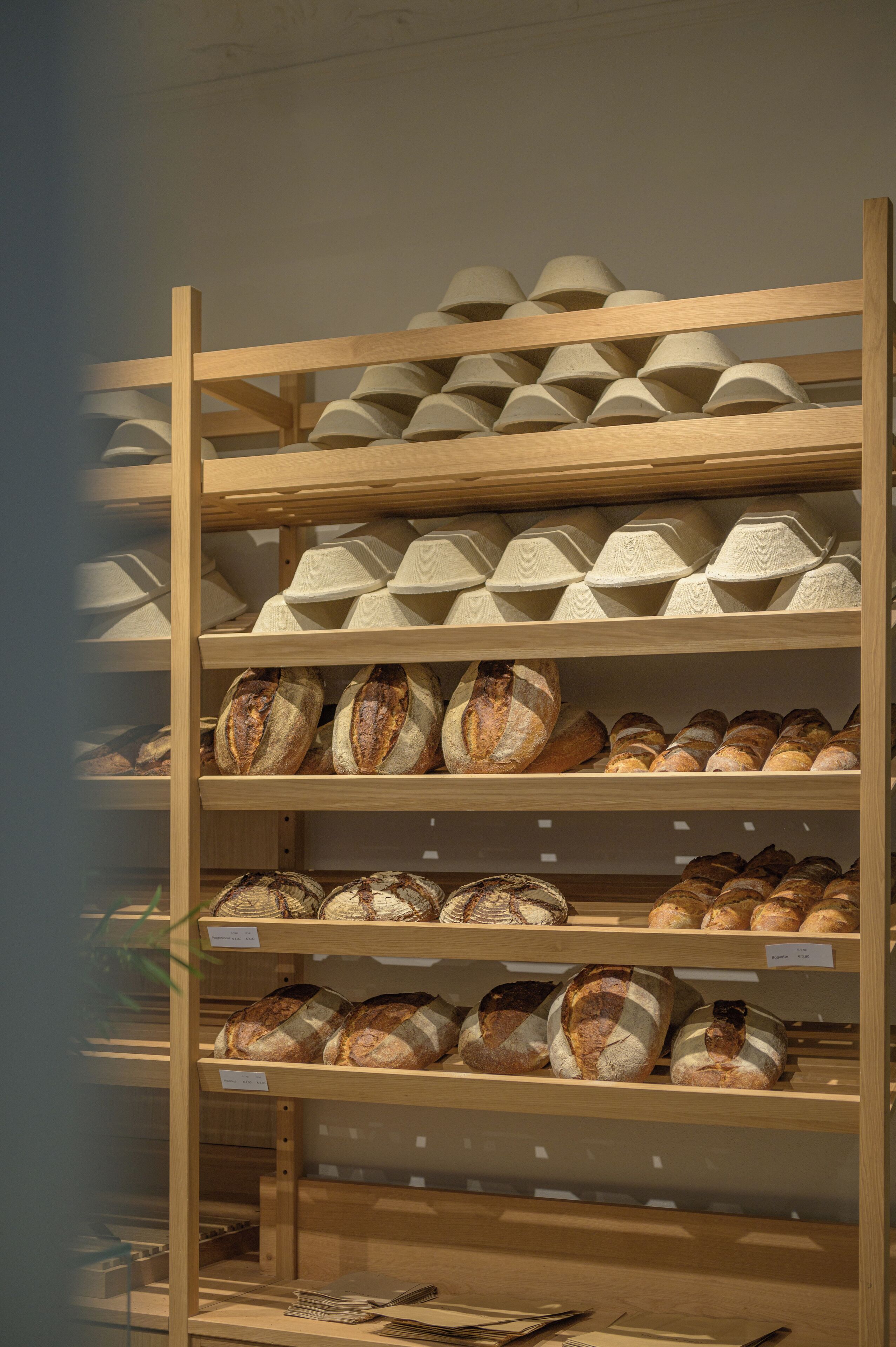 Un escaparate de panadería con diversos tipos de pan y pasteles en estantes de madera.