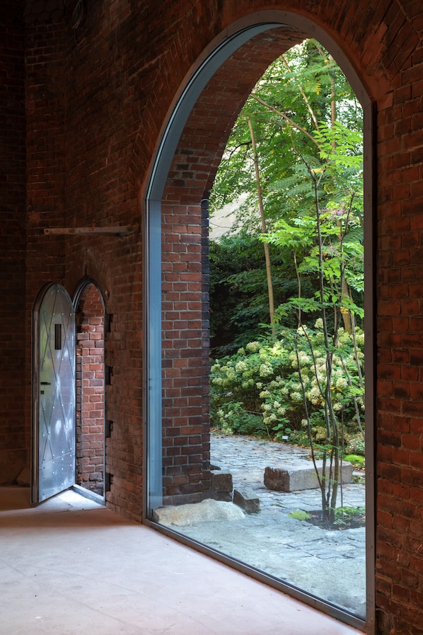 Interior de ladrillo con un amplio ventanal de arco que da a un jardín.