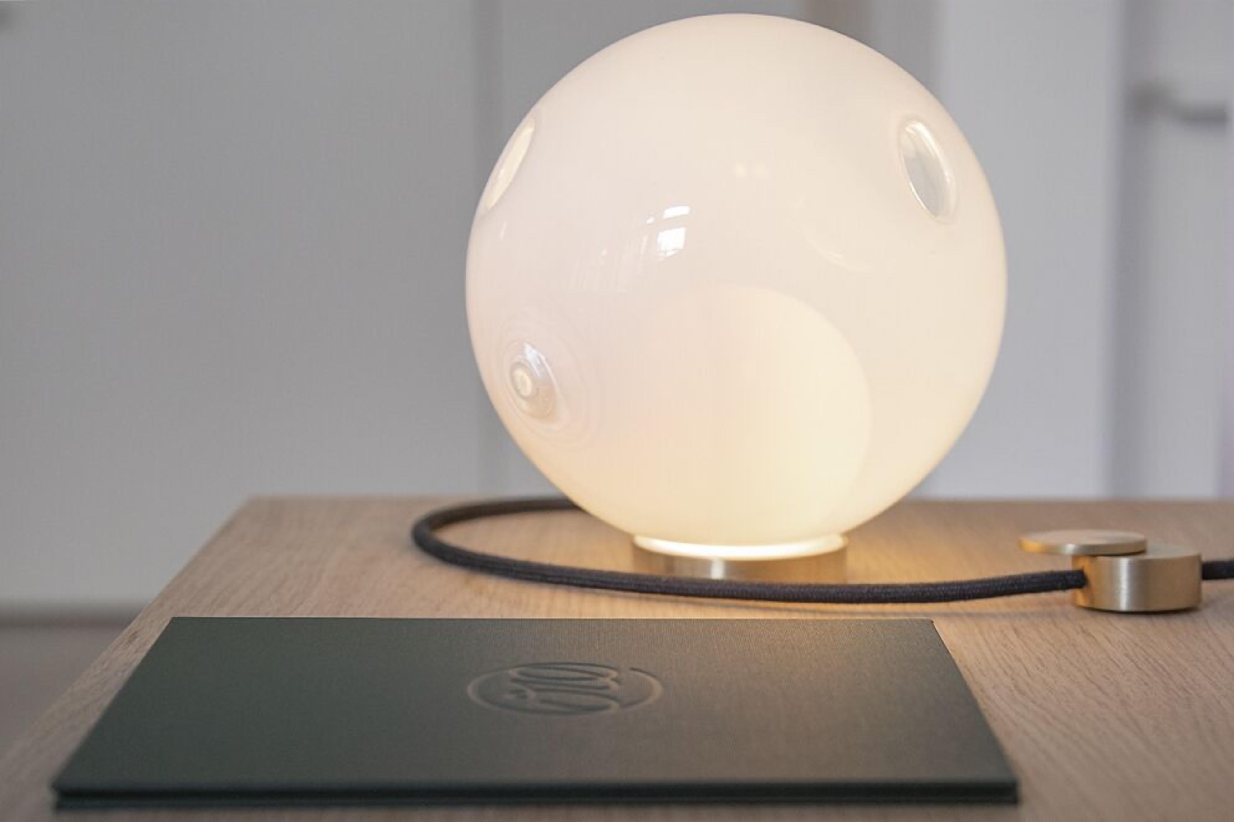 A spherical lamp with a cord on a wooden table.