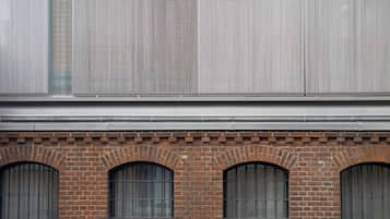 Fachada de edificio con una sección inferior de ladrillo y una sección superior de metal con líneas verticales.