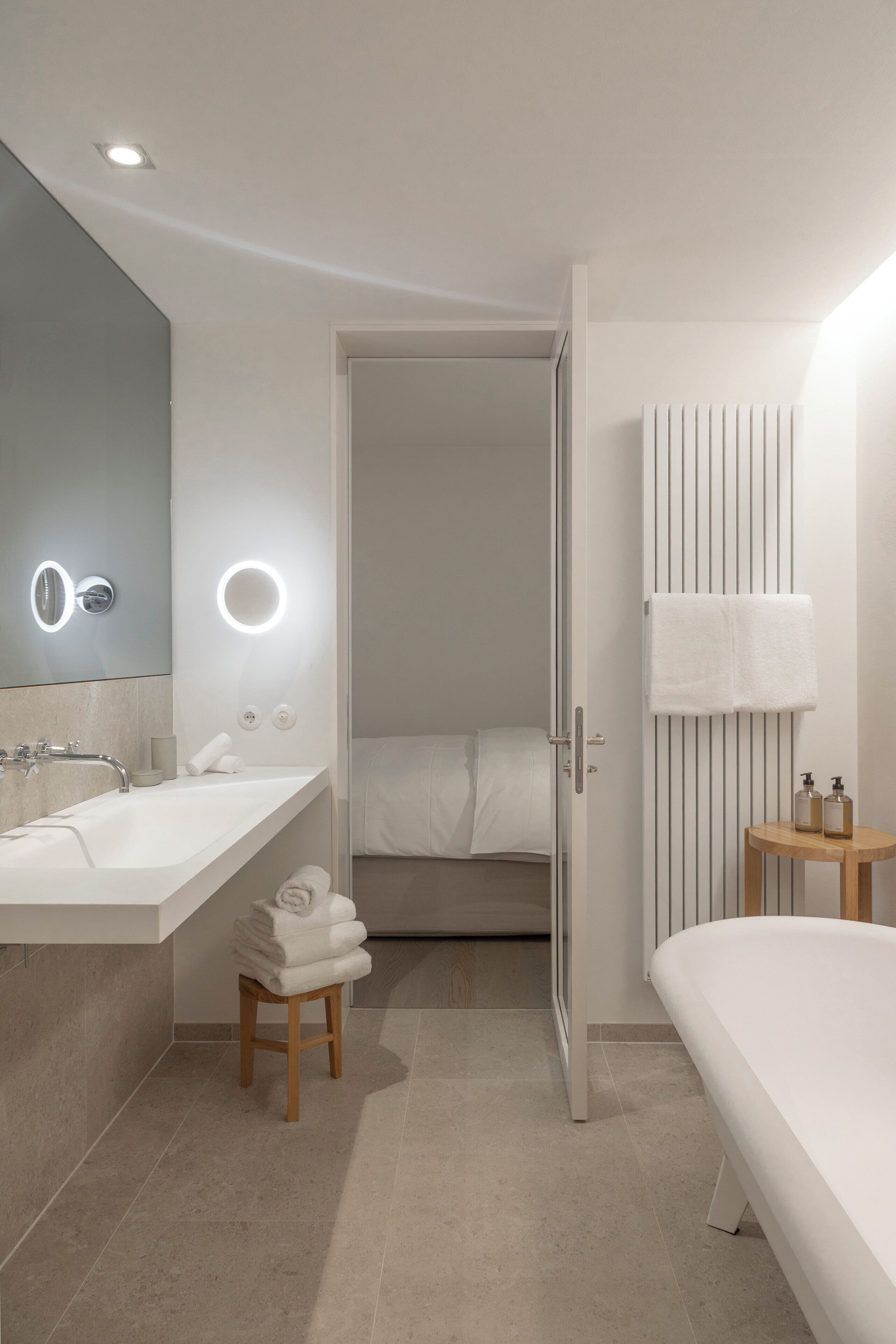 A modern bathroom with a large mirror, two sinks, a toilet, and a shower area.