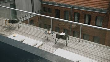 En takterrass med ett trädäck, två bord och två stolar.