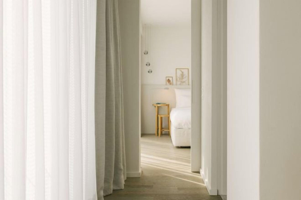 A hallway leading to a bedroom with a bed, a nightstand, and a small table.
