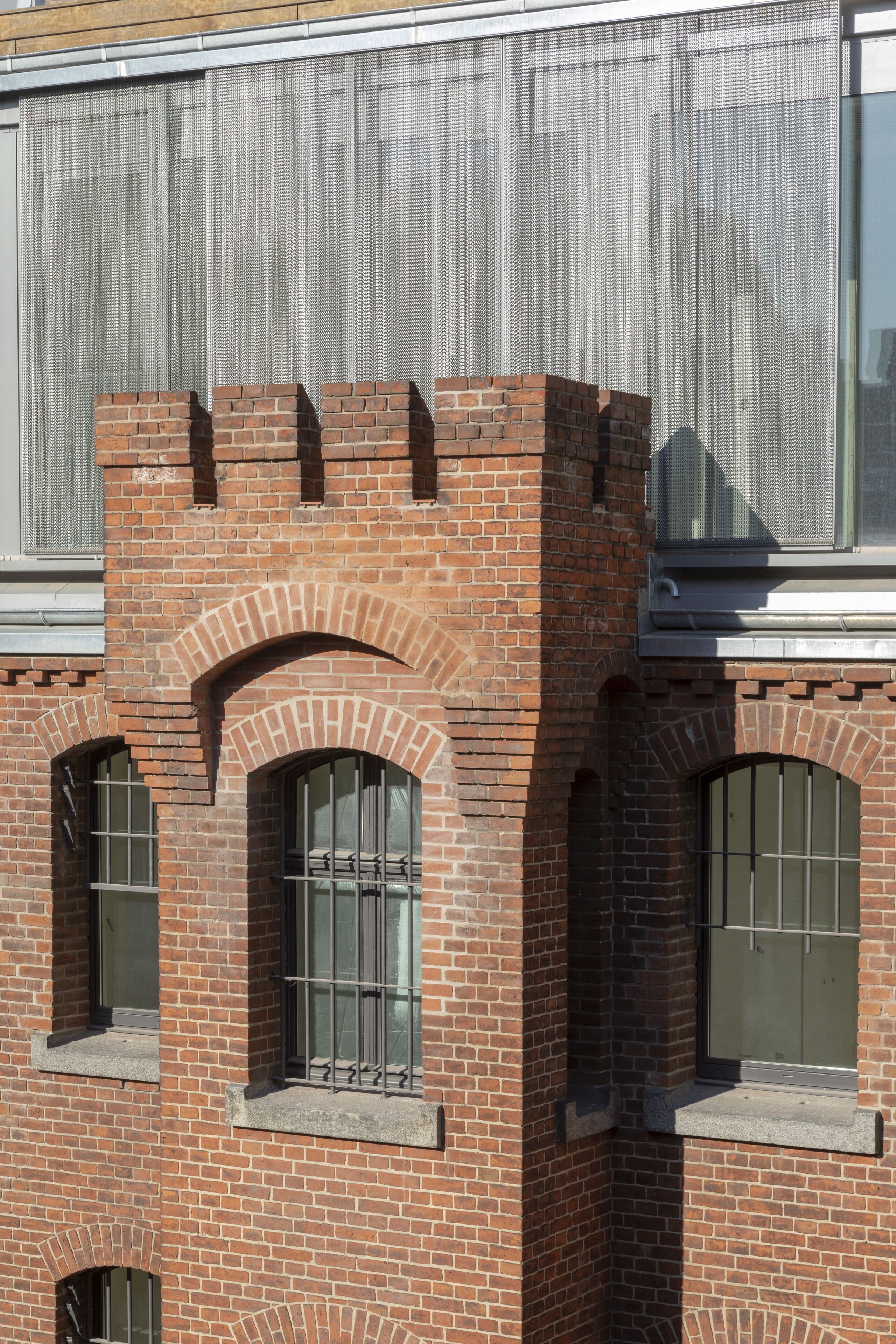 A brick building with arched windows and a metal mesh screen.