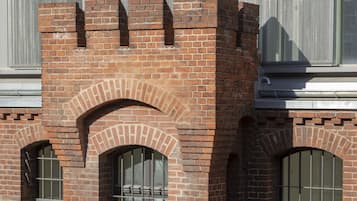 A brick building with arched windows and a metal mesh screen.