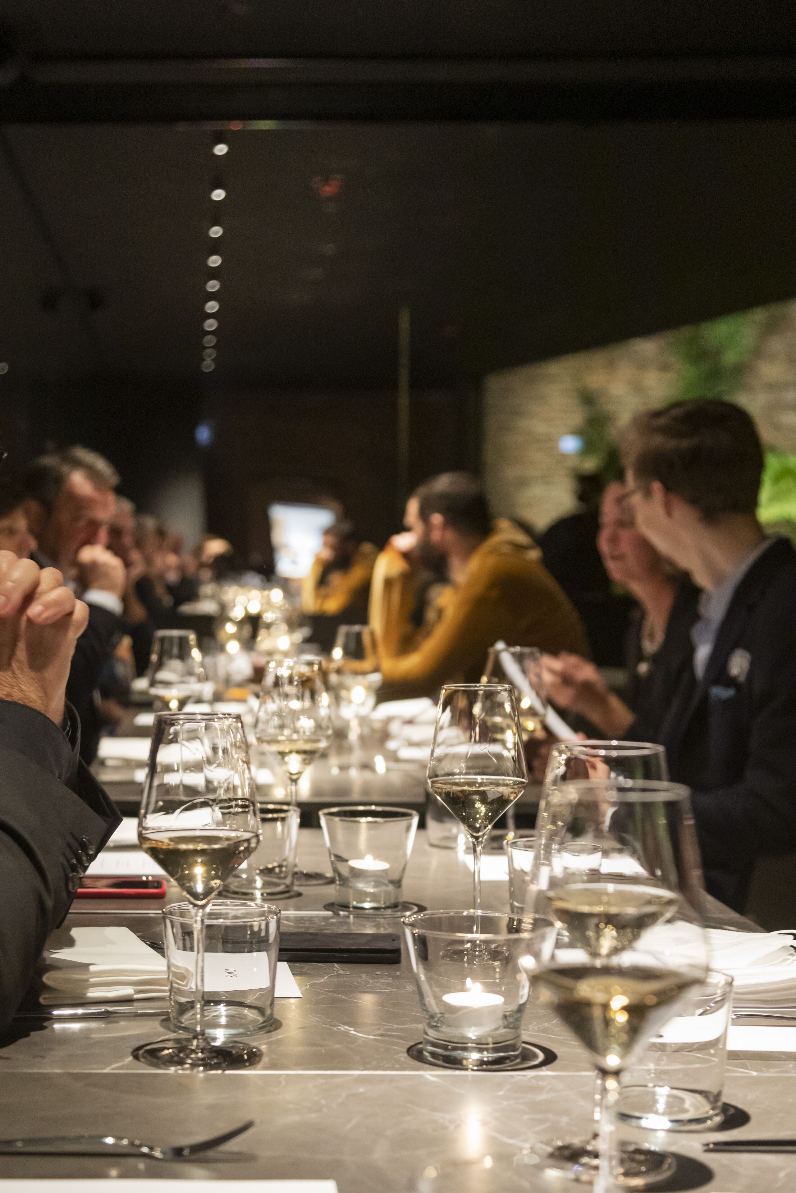 Une longue table à manger, ornée de plusieurs verres à vin et d’une bougie.