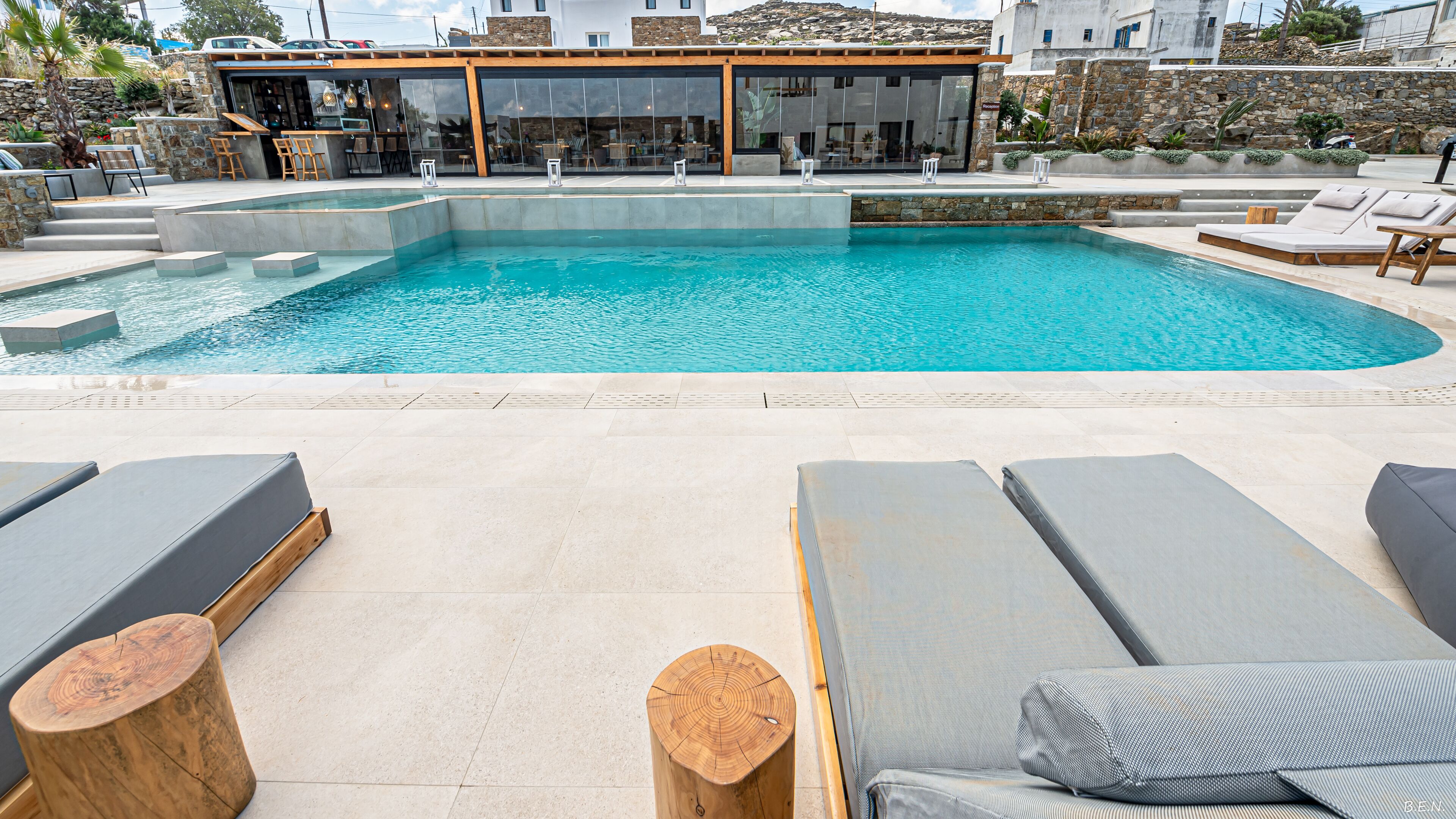 Ein moderner Poolbereich mit Liegestühlen und einer Bar.