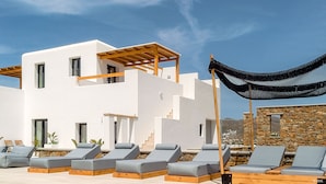 A modern building with a white exterior, a wooden pergola, and a stone wall. - Le Palme Mykonos (Mykonos)