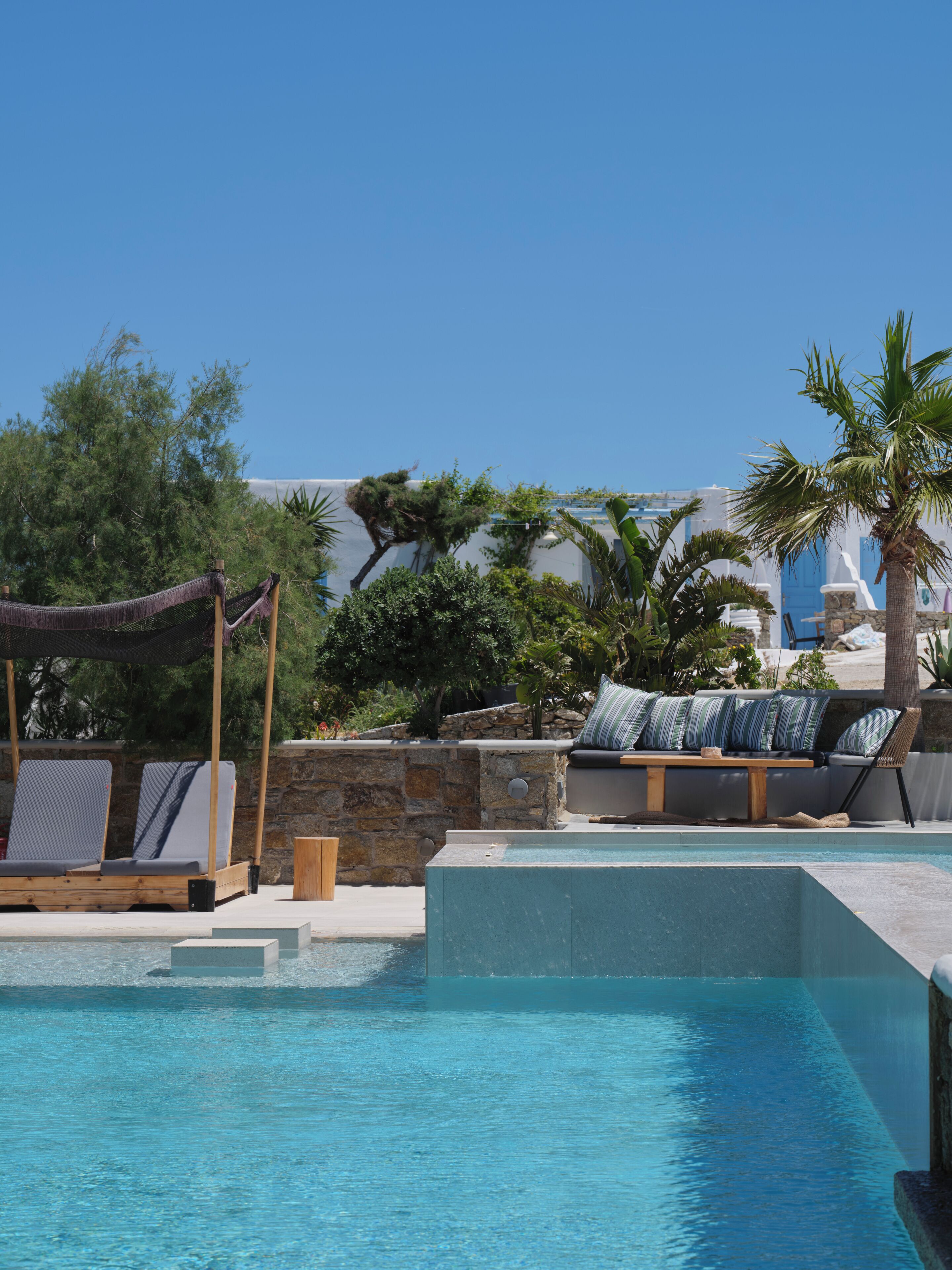 Una piscina al aire libre, sombrillas, sillones reclinables de piscina