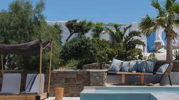 Una piscina al aire libre, sombrillas, sillones reclinables de piscina