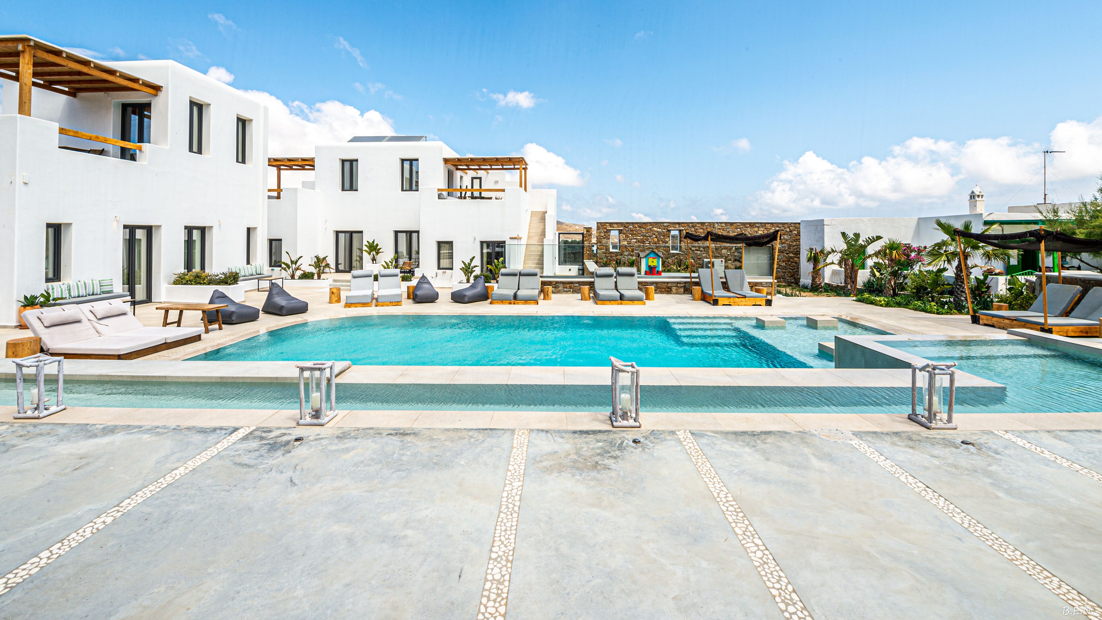 Un área de piscina moderna con varias sillas de descanso y una piscina azul cristalina.